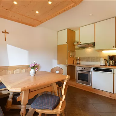 Eine gemütliche Küche mit einem Holztisch und Stühlen. Die Wände sind hell, und es gibt moderne Küchengeräte.