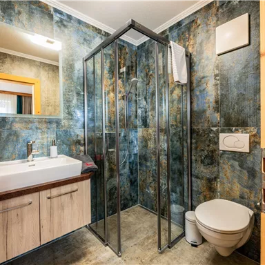 Ein modernes Badezimmer mit einer Glasdusche und einem Waschbecken. Die Wände sind in einem einzigartigen blauen Muster gestaltet.