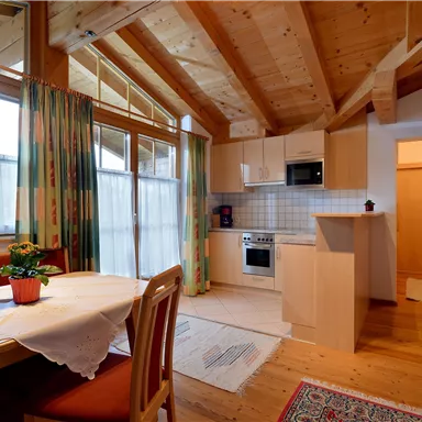 Eine gemütliche Küche mit einem Essbereich. Helle Holzverkleidung und große Fenster sorgen für eine einladende Atmosphäre.