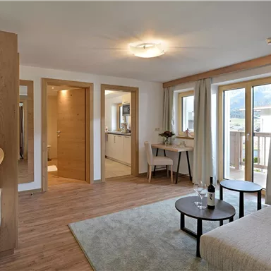 Ein helles Wohnzimmer mit modernen Möbeln und großen Fenstern. Der Raum ist geschmackvoll eingerichtet und wirkt einladend.