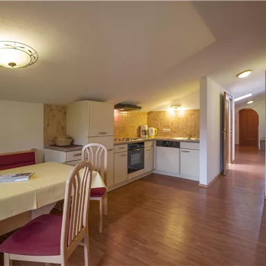 Eine helle und moderne Küche mit einem Esstisch und Stühlen. Der Raum hat Holzböden und eine gemütliche Atmosphäre.