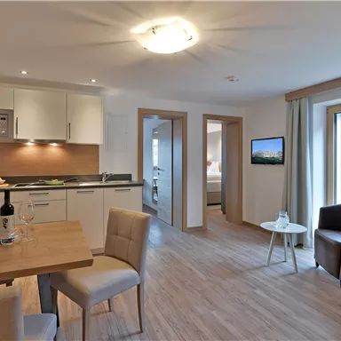 Eine moderne Wohnung mit einem Essbereich und einer offenen Küche. Das Wohnzimmer ist hell und freundlich mit Zugang zu einem Balkon.