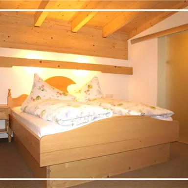 Ein gemütliches Schlafzimmer mit einem großen Bett und Holzdecke. Der Raum verfügt über eine helle Atmosphäre und einen Zugang zum Badezimmer.