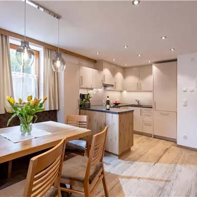 A modern kitchen with a dining area. The table is decorated with a vase full of tulips.