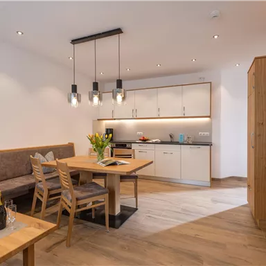 A modern living room with a cozy seating area and a dining area. The kitchen is well-equipped, and the lighting creates an inviting atmosphere.