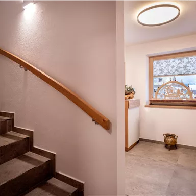 An inviting hallway with a staircase and a bright window. The decor is modern and cozy.