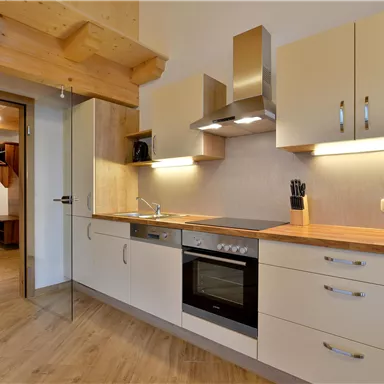 A modern kitchen with wooden shelves and stylish appliances. The space is bright and inviting, perfect for cooking and spending time.