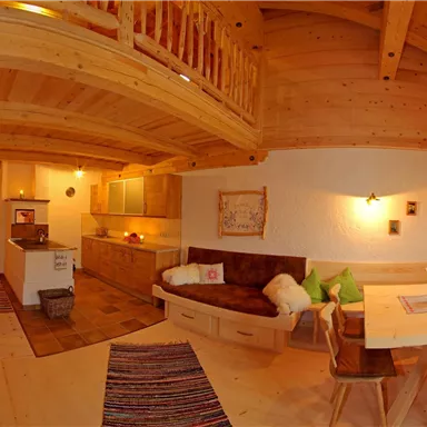 Ein gemütliches Holzhaus mit offener Wohnküche und Essbereich. Die warmen Farben und die Holzdetails schaffen eine einladende Atmosphäre.