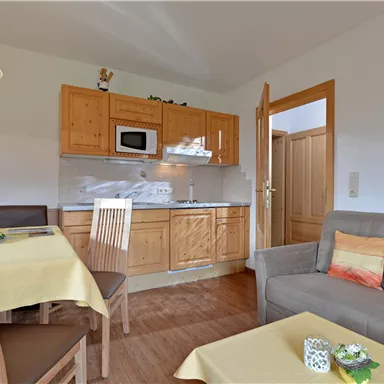 Eine gemütliche Wohnung mit einer Holz-Küche, einem Esstisch und einer komfortablen Sitzgelegenheit. Der Raum ist hell und freundlich gestaltet.