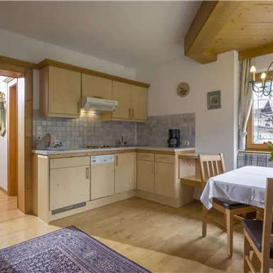 Eine helle Küche mit modernem Holzdesign und einem Esstisch. Es gibt einen schönen Blumenstrauß auf dem Tisch und eine gemütliche Atmosphäre.