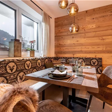 A cozy dining area with wood paneling and modern pendant lights. The table is lovingly set and offers seating for several people.