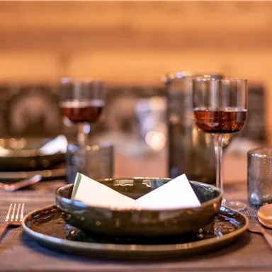 A stylishly set table with dark plates and glasses. The atmosphere feels cozy and inviting.