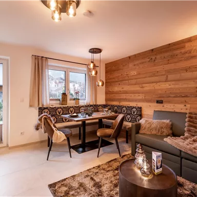 A modern living room with wooden paneling and elegant furnishings. The space is well-lit and features a cozy dining area as well as a comfortable seating corner.