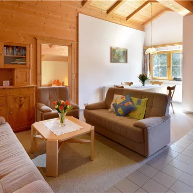 Ein gemütliches Wohnzimmer mit Holzwänden und einem hohen Dach. Zwei Sofas und ein Tisch schaffen eine einladende Atmosphäre.