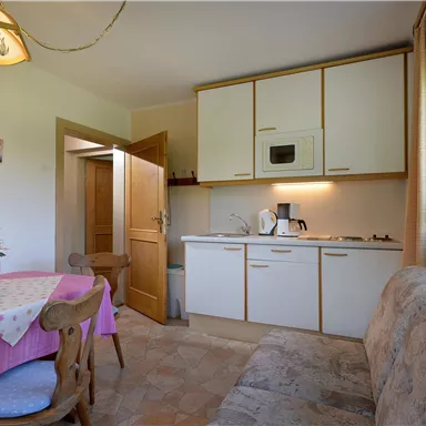 Eine helle und gemütliche Küche mit einem Essbereich. Der Raum ist gut ausgestattet und mit einem Tisch und Stühlen sowie einer Couch versehen.