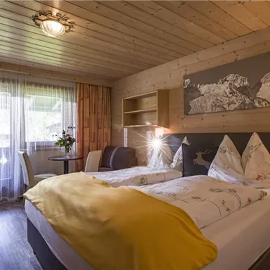 Ein gemütliches Zimmer mit Holzverkleidung und zwei Betten. Fenster mit Blick auf die Natur und eine entspannende Atmosphäre.