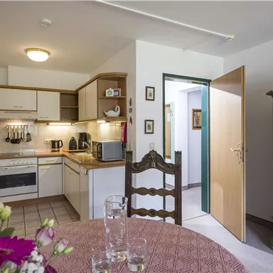 Eine gemütliche Küche mit einem Esstisch und einem traditionellen Schrank. Der Raum ist hell und freundlich gestaltet.