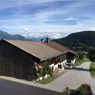 A traditional house in the countryside with a beautiful landscape in the background. The mountains and the clear sky give the scene a peaceful atmosphere.