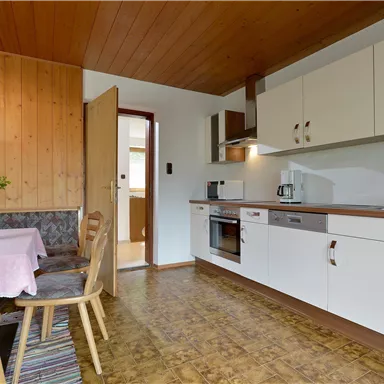 A cozy kitchen with a dining area. Bright furniture and wood paneling create an inviting atmosphere.