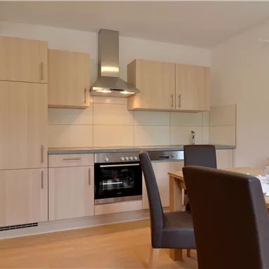 Eine moderne Küche mit Holzschränken und einem Herd. Der Essbereich umfasst einen Tisch mit Stühlen und einen schönen Blick aus dem Fenster.