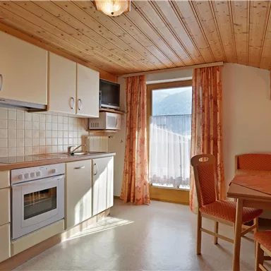 Eine moderne Küche mit Holzverkleidung und großen Fenstern. Der Essbereich ist gemütlich mit einem Tisch und Stühlen ausgestattet.