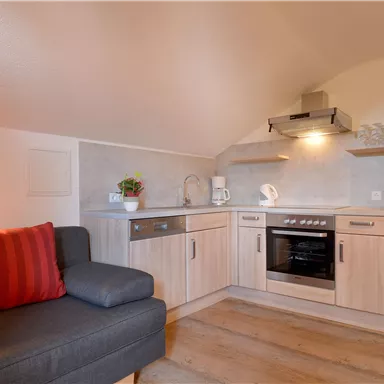 Eine moderne Küche mit Holzschränken und einer komfortablen Sitzecke. Die Einrichtung ist hell und einladend, ideal für eine gemütliche Atmosphäre.