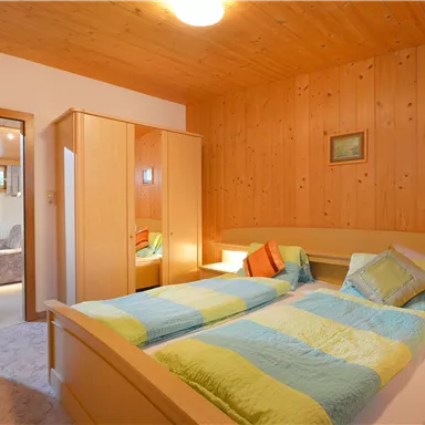 Ein gemütliches Schlafzimmer mit Holzverkleidung und zwei Einzelbetten. Die Wände sind warm und einladend, und es gibt eine sanfte Beleuchtung.