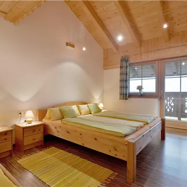 Ein gemütliches Schlafzimmer mit Holzdekor und zwei Betten. Große Fenster bieten einen Blick nach draußen und lassen viel Licht herein.