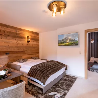 A cozy bedroom with a double bed and warm wooden walls. The room is modernly furnished and has a pleasant atmosphere.