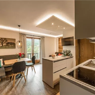 A modern kitchen with an inviting dining area. Large windows provide plenty of light and offer a view of the outside world.