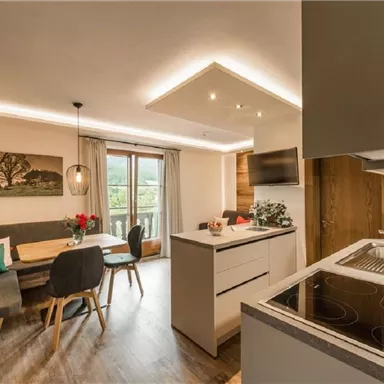 A modern kitchen with an inviting dining area. Large windows provide plenty of light and offer a view of the outside world.