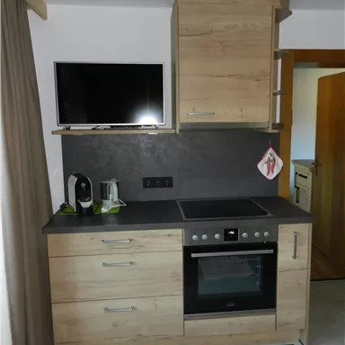 Eine moderne Küche mit Holzschränken und einem Herd. Der Boden ist mit einem bunten Teppich dekoriert.