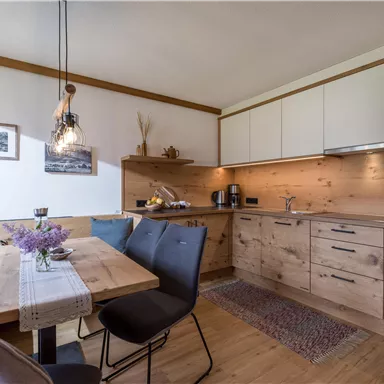 A modern kitchen with wooden surfaces and a dining area. The atmosphere is cozy and inviting.