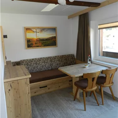 Ein gemütlicher Essbereich mit einem Holztisch und Stühlen. Im Hintergrund befindet sich eine Sitzecke und ein Kunstwerk an der Wand.