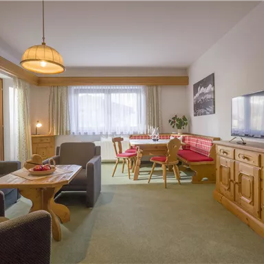 Ein gemütliches Wohnzimmer mit modernen Möbeln und einem großen Fenster. Der Raum ist hell und einladend, ideal zum Entspannen.