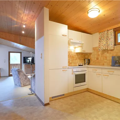 Eine moderne Küche mit hellen Möbeln und Holzverkleidung. Der Raum ist gut beleuchtet und offen gestaltet.