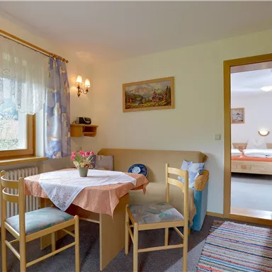 Ein gemütlicher Essbereich mit einem Tisch und Stühlen. Im Hintergrund ist ein Zugang zu einem Schlafzimmer zu sehen.