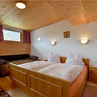 Ein gemütliches Schlafzimmer mit Holzverkleidung und zwei Betten. Das Zimmer ist hell und freundlich, mit gemütlichen Kissen und Vorhängen.