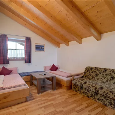 Ein gemütlicher Raum mit Holzdecke und zwei Einzelbetten. Ein Sofa und ein Tisch runden die ausreichende Ausstattung ab.