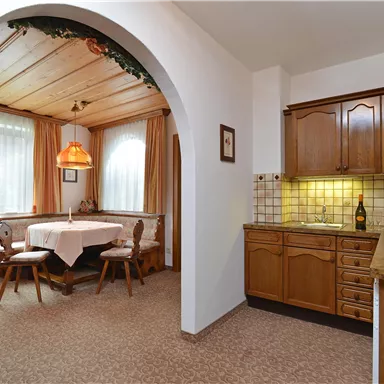 Eine gemütliche Küche mit Holzschränken und einem Essbereich. Der Raum ist hell beleuchtet und freundlich gestaltet.