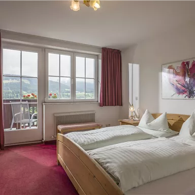 Ein gemütliches Schlafzimmer mit zwei Betten und einer herrlichen Aussicht auf die Umgebung. Große Fenster lassen viel Licht herein und sorgen für eine einladende Atmosphäre.