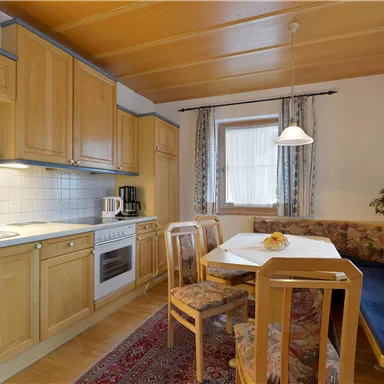 Eine helle Küche mit Holzschränken und einem Esstisch. Die Einrichtung ist gemütlich und einladend.