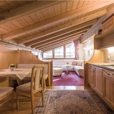 Eine gemütliche Küche mit Holzdetails und einem Esstisch. Das lichtdurchflutete Wohnzimmer ist mit bequemen Möbeln ausgestattet.