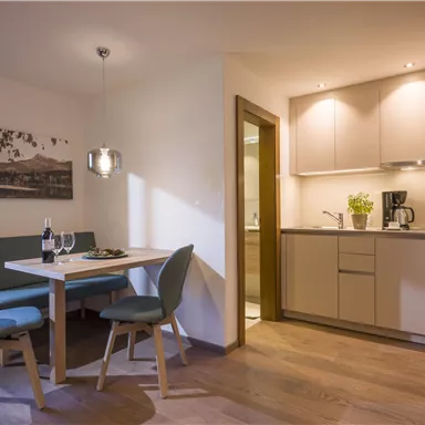 A modern kitchen unit with a dining table and chairs. The space is designed to be friendly and bright.