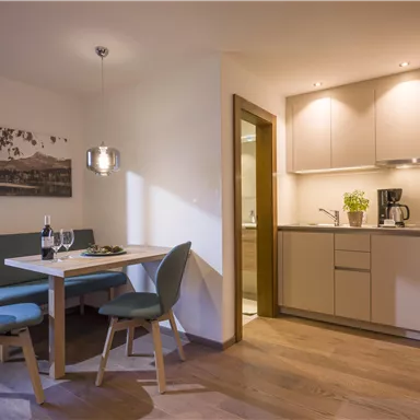 A modern kitchen unit with a dining table and chairs. The space is designed to be friendly and bright.