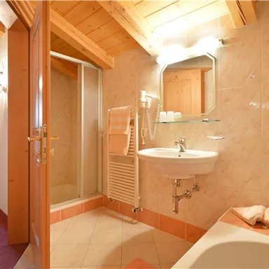 Ein modernes Badezimmer mit Dusche und Waschbecken. Helle Fliesen und Holzdetails sorgen für eine einladende Atmosphäre.