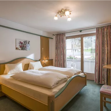 Ein gemütliches Schlafzimmer mit zwei Betten, einem Schreibtisch und einem Fenster mit Blick nach draußen. Die Einrichtung ist hell und einladend.