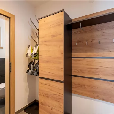 Ein moderner Flur mit Holzregalen und einer Tür zu einem Badezimmer. An der Wand hängen verschiedene Gegenstände.