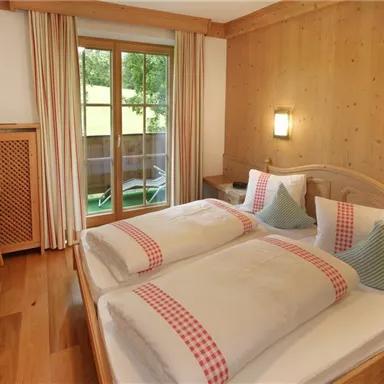 Ein gemütliches Schlafzimmer mit zwei Einzelbetten und holzverkleideten Wänden. Der Raum verfügt über einen kleinen Tisch und einen Zugang zu einem Balkon.