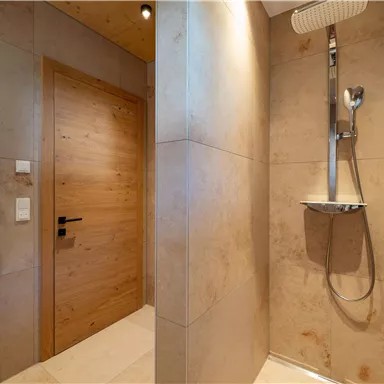 Ein modernes Badezimmer mit einer Dusche und einer Holzschiebetür. Die Wände sind in neutralen Farben gehalten und vermitteln ein elegantes Ambiente.